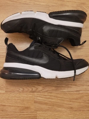 Nike Air Max svarta sneakers - Snygga svarta Nike Air Max sneakers med vit sula och synlig Air-enhet i hälen. Skorna har en klassisk låg siluett, mesh- och syntetmaterial samt svarta skosnören. Ikonisk Swoosh-logga på sidan och AIR-detalj på plösen.