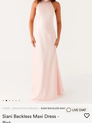 Balklänning  - Säljer en elegant rosa långklänning i glansigt satinmaterial. Den sitter uppe med en rosett bakom nacken. Aldrig använd, storlek xs, köpt för 1080kr säljer för 800kr