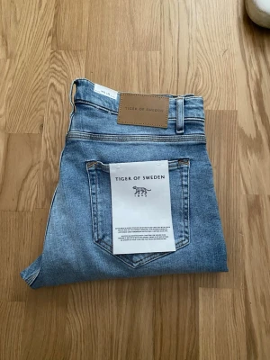 Ljusblå slim fit jeans från Tiger of Sweden - Hej, Säljer ett par jeans från Tiger Of Sweden helt oanvända jeansen har en fin tvättning på låren och mycket snygga små detaljer byxorna är storlek 32/32 slim fit nypris är 1600 kvitto finns och alla prislappar är kvar hör av er om ni undrar något! pris är ej hugget i sten!