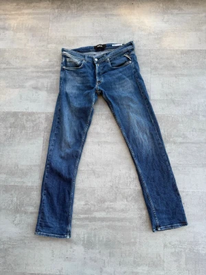 Blå Replay Grover straight fit jeans - Snygga blå jeans från Replay, modell Grover med straight fit. Klassisk femficksdesign, normal midja och knappgylf. Jeansen har tvättade detaljer för en cool look. Perfekta till sneakers eller boots.