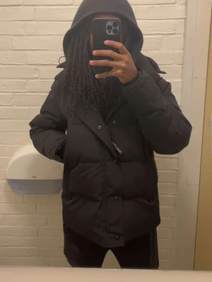 Canada Goose jacka - Säljer denna svarta Canada goose pufferjackan med huva och päls och snygga detaljer. Jackan har knappar framtill, långärmade ärmar och quiltad design. Insidan har praktiska axelremmar med logga. Perfekt för kalla vinterdagar och passar med allt. Det bara att höra av sig om nån är intresserad.