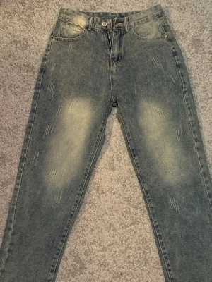 Fasshionjeans - Snygga  jeans med slitningar och ljusa partier på lår och bak. Rak/straight passform. Klassisk femficksmodell med raka ben och knappgylf. Jeansen har en cool tvättad look och är perfekta för en avslappnad stil. Märket fashion jeans. 