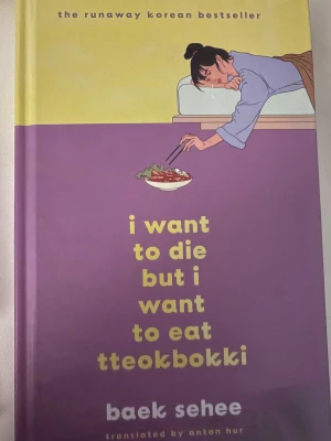 I Want to Die but I Want to Eat Tteokbokki - En koreansk roman med hård pärm i lila och gul design. Boken har en illustrerad framsida med en person som sträcker sig efter en skål tteokbokki. Texten är på engelska och boken är översatt av Anton Hur.