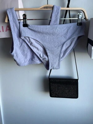 Ljuslila bikini med ribbad struktur - Trendig bikini i ljuslila med ribbad struktur. Överdelen har breda axelband och underdelen är klassiskt skuren. Perfekt för sommaren och strandhäng. Materialet känns mjukt och stretchigt för en bekväm passform.