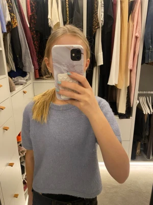 Ljusblå stickad kortärmad topp - Superfin ljusblå stickad topp med korta ärmar och rund halsringning. Mjuk och skön, perfekt till jeans eller kjol. Enkel och stilren design som passar till många olika looks.