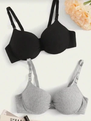 2-pack bh svart och grå med vaddering - Två bhar i svart och grått med justerbara axelband och vadderade kupor. Båda har hak- och hyskknäppning bak och slät design utan spets. Materialet ser ut att vara mjuk bomullsblandning, perfekt för en enkel och bekväm look.