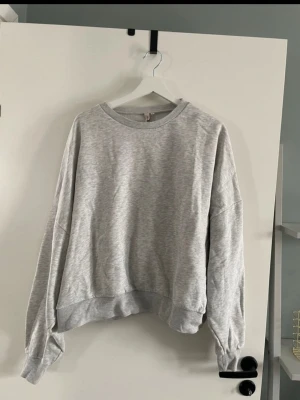 Grå sweatshirt från Nelly - En basic grå sweatshirt från Nelly med rund halsringning och ribbade muddar vid ärmslut och nederkant. Oversized passform som ger en avslappnad vibe. Perfekt att matcha med jeans eller mjukisbyxor för en chill look.