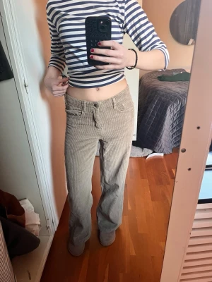 Bruna manchesterbyxor - Säljer ett par beige manchesterbyxor med klassisk femficksmodell. Byxorna har breda revärer och stängs med knapp och dragkedja. Perfekta för dig som gillar retrostil och vill ha ett par sköna byxor i mjukt manchestertyg.jag har lagt upp byxorna ganska mycket kanske 5cm 