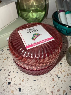 Rosa glasburk - Emily in Paris🩷 - Säljer en rund, rosa glasburk med Emily in Paris-motiv. Burken har en räfflad design. Perfekt för att förvara smycken i eller som snygg inredningsdetalj i badrummet eller på sminkbordet. Burken är ca 8 cm i diameter. 