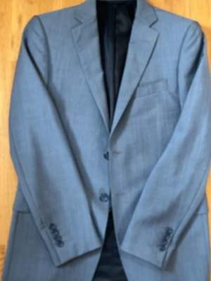 Grå kavaj från Balmain Paris - Stilren grå kavaj från Balmain Paris med klassisk passform och tvåknäppning. Kavajen har en bröstficka, två framfickor och helsvart innerfoder med diskret Balmain-logga. Perfekt för dig som vill ha en tidlös och elegant look.