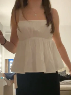 Vit volang topp - Söt vitt linne med smala axelband som är justerbara. Är i linne och därför lite skrynklig på andra bilden, har endast användt den en gång så i nytt skick