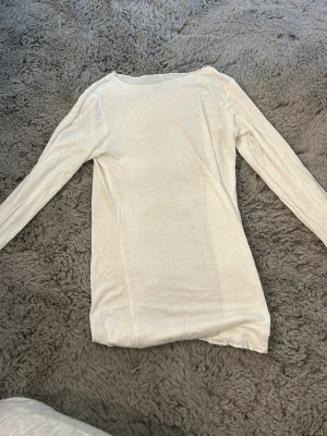 Vit långärmad topp från Stories - En enkel och stilren vit långärmad topp från Stories i storlek XS. Toppen har rund halsringning och är gjord i ett mjukt, tunt material som känns skönt mot huden. Perfekt att matcha med jeans eller kjol för en clean look.