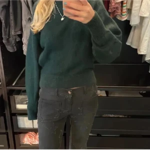 Mörkgrön stickad tröja från other stories - Mysig mörkgrön stickad tröja med rund halsringning och långa ärmar. Tröjan har en enkel och stilren design utan synliga detaljer eller mönster, perfekt för lager-på-lager under kyliga dagar.från Other stories 