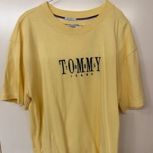 Gul t-shirt från Tommy Hilfiger  - Gul t-shirt från Tommy Hilfiger med broderad logga på bröstet. Klassisk rund halsringning och avslappnad passform. Perfekt för en enkel och stilren look.