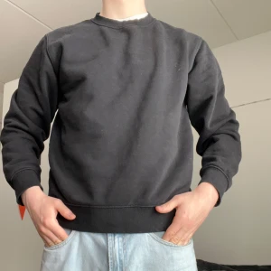 Sweatshirt Weekday - En stilren svart sweatshirt med rund hals från Weekday, grymt skick. Perfekt för en avslappnad look och enkel att matcha med jeans eller andra byxor.