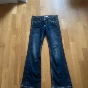 Mörkblå jeans med paljett-detaljer från Gina Tricot - Säljer ett par mörkblå jeans från Gina Tricot med snygga paljett-detaljer på bakfickorna. Byxorna har vita kontrastsömmar och klassisk femficksmodell. Perfekta för dig som vill sticka ut lite extra med coola detaljer.