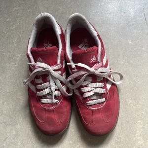 Röda Adidas Spezial sneakers - Säljer ett par röda Adidas Spezial sneakers med vita ränder och snörning. Skorna har mockaöverdel, vit Adidas-logga på hälen och klassisk gummisula. Perfekta för dig som gillar retrostil och vill sticka ut med färg.kan alltid diskutera pris!