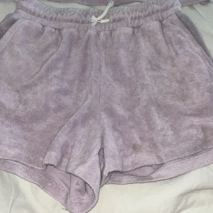 Ljuslila frottéset från Lindex - Mysiga ljuslila shorts och tröja i frottématerial från Lindex. De har resår och dragsko i midjan samt fickor på sidorna. Perfekta för varma dagar eller som chillplagg hemma.