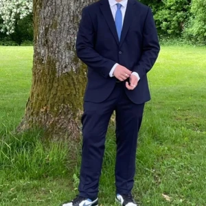 Mörkblå kostym med kavaj och byxor - Säljer en klassisk mörkblå kostym med matchande kavaj och byxor. Kavajen har två knappar framtill och smal passform. Perfekt för formella tillfällen som bal eller student.