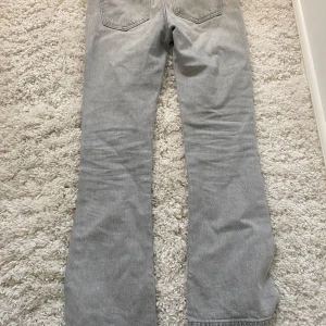Grå bootcut jeans från Gina Tricot - Säljer ett par gråa bootcut jeans från Gina Tricot x Izaandelle. Jeansen har klassisk femficksdesign, normal passform och utsvängda ben. Perfekta för dig som gillar en avslappnad men trendig stil.