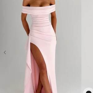 Ljusrosa offshoulder långklänning med slits, helt oanvänd - Supersnygg ljusrosa långklänning/balklänning med offshoulder och figurnära passform. Klänningen har en hög slits framtill och vackra draperingar över byst och midja. Perfekt för bal eller fest!