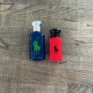Ralph Lauren Polo Blue och Polo Red parfymflaskor - Två parfymflaskor från Ralph Lauren: en blå flaska med silverlock och grön logga samt en röd flaska med svart lock och svart logga. Den blå flaskan har även en stor gul siffra 1 på baksidan. Klassisk design med sportig känsla. Ungefär 40 ml kvar i polo blue och 20 i polo red