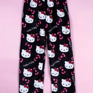 Hello Kitty mjukisbyxor i fleece - Supermjuka svarta mjukisbyxor med Hello Kitty-motiv och rosa detaljer. Byxorna har ett gulligt mönster med Hello Kitty-ansikten och rosetter över hela tyget. Perfekta för mysiga dagar hemma. ALLA STORLEKAR.