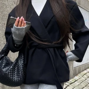 Svart kappa från Missäy  - Snygg svart kappa från Missäy med knytband i midjan. Perfekt för en stilren look. Kappan har långa ärmar och en klassisk krage. Den har endast användts ett fåtal gånger så ser ut som ny! Storleken är Xs men passar även S 