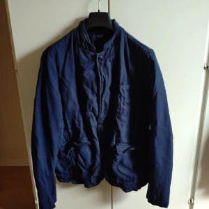 Blå kavajjacka från Paul Smith Jeans - Säljer en stilren blå kavajjacka från Paul Smith Jeans i storlek M. Jackan har knäppning framtill, ståkrage och fickor på sidorna. Perfekt för dig som vill ha en snygg och avslappnad look med klassiska detaljer.Galge ingår ej. Nypris 3299 kr.