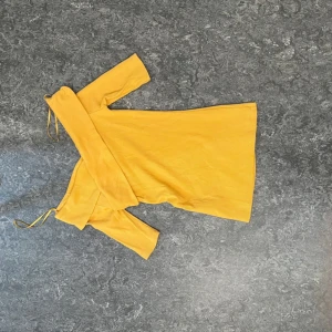 Gul offshoulder klänning från Gina Tricot - Säljer en snygg gul offshoulder klänning från Gina Tricot i ribbad bomullsmix. Klänningen har smal passform och långa ärmar, perfekt för dig som vill sticka ut med färg. Superskön och trendig modell!