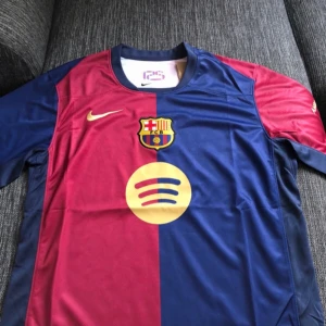 FC Barcelona matchtröja 24/25 2x Exemplar - Säljer en FC Barcelona fotbollströja från Nike med klassisk röd och blå design. Tröjan har klubbmärke och Nike-logga på bröstet samt sponsortryck på magen. Tillverkad i Dri-FIT-material för bra komfort. Perfekt för dig som älskar Barca!