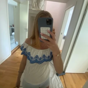 Vit offshoulder topp med blå brodyr💙 - Superfin vit offshoulder topp med bred volangkant och blå broderade blommor längs axlarna. Toppen är ifrån HM. Jättefin till sommaren🤍