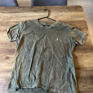 Grön t-shirt från Polo Ralph Lauren - Snygg grön t-shirt från Polo Ralph Lauren med klassisk passform och korta ärmar. T-shirten har en liten broderad logga på bröstet och är tillverkad i mjuk bomull. Perfekt för en avslappnad och stilren look.