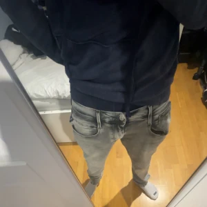 Ljusgrå replay Anbass slim fit - Snygga ljusgrå jeans från Replay med klassisk femficksdesign och raka ben. Jeansen har diskreta slitningar och tydliga sömmar, samt Replay-logga vid fickan. Säljer pga att den är för stor. Nypris 1700 32/32. Meddela privat för mer info eller bilder