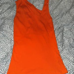 Orange ribbad linnetopp från InWear - Säljer en snygg orange ribbad linnetopp från InWear. Toppen har djup rundringning och ärmlös design, perfekt för att styla med jeans eller kjol. Materialet är mjukt och stretchigt för en bekväm passform.