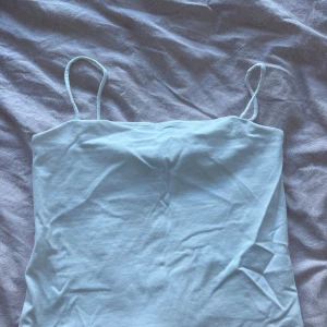 Vit linnetopp från Gina Tricot - En enkel och stilren vit linnetopp från Gina Tricot i storlek S. Toppen har tunna axelband och är tillverkad i mjuk bomull, perfekt för varma dagar eller att styla lager på lager. Snygg att matcha med jeans eller kjol för en clean look.