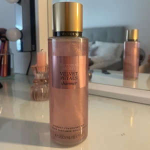 Victoria's Secret Velvet Petals Shimmer - Parfymmist i en snygg rosa skimrande flaska från Victoria's Secret. Velvet Petals Shimmer har doft av blommor och mandel, med en glittrig finish som ger extra glow. Flaskan rymmer 250 ml och har en guldig kork. Perfekt för dig som vill dofta fräscht och sticka ut.