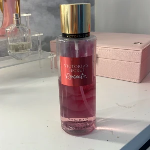 Victoria's Secret Romantic mist - Fräsch body mist från Victoria's Secret i doften Romantic. Flaskan är genomskinlig med rosa vätska och har en guldig kork. Doften har inslag av rosa blomblad och mjuk mysk. Rymmer 250 ml och har en snygg, modern design.