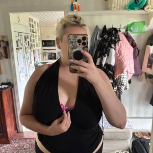 Svart halterneck topp från BikBok XL - Svart halterneck topp från BikBok i storlek XL. Djup v-ringning framtill och öppen rygg, knyts i nacken. Snygg och enkel modell som sitter tight över bysten och har en croppad känsla. Perfekt för dig som gillar att sticka ut med en klassisk svart topp.