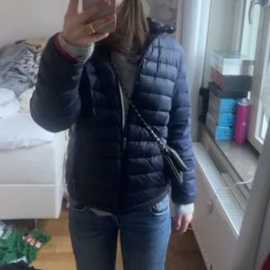 Mörkblå pufferjacka från Ralph Lauren - Säljer en mörkblå pufferjacka från Ralph Lauren med dragkedja framtill och diskret logga på bröstet. Jackan är quiltad och har en klassisk passform med långa ärmar och huva. Perfekt för kyliga dagar och enkel att styla till jeans eller mjukis.