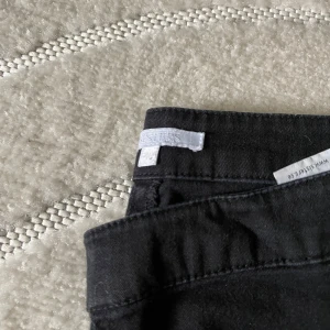 Svarta byxor med dragkedja i sidan - Svarta byxor från Sisters Point i slim fit-modell med dragkedjor i sidorna. Byxorna är tillverkade i ett mjukt bomullsmaterial med lite stretch och har en clean look utan synliga fickor. Perfekta för en stilren och enkel outfit.