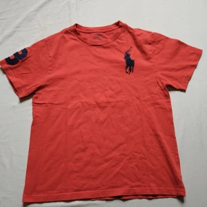 Röd Ralph Lauren T-shirt  - Tjo gubbar en fet Ralph Lauren T-shirt i fin röd färg med ett stort märke i rött och en fin trea på din höger. Storlek XXS/XS. Väldigt bra skick och perfekt för just dig 😉. Kolla gärna profilen för mycket mer Ralph Lauren kläder och följ gärna också ❤️. Ha de göttttttt 🥳. Har en liten fläck. Fråga bara om du vill ha bild.