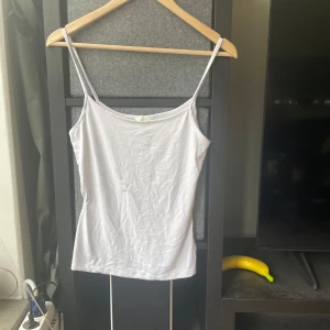 Vit linnetopp från H&M, storlek S - Enkel och stilren vit linnetopp från H&M i storlek S. Toppen har smala axelband och rak passform, perfekt att matcha med jeans eller kjol. Tillverkad i mjuk bomull som känns skön mot huden.