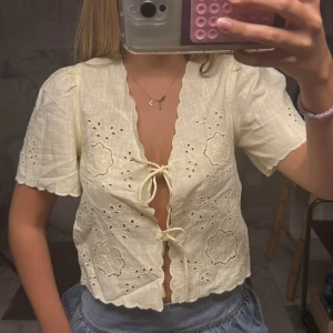Broderad blus med knyt och volang - Söt ljusgul blus med broderade blommor, korta ärmar och volangkant. ❤️ aldrig använd och lappen är kvar! Slutsåld 