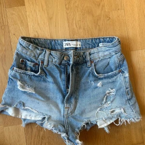 Blå slitna jeansshorts från Zara - Snygga blå jeansshorts från Zara med slitna detaljer och fransig kant. Knappt använda, nypris runt 400! 