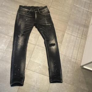 Dondup jeans - Säljer ett par svarta skinny jeans från Dondup med coolt sliten look, färgstänk och slitningar på knäna. Dem är väldigt trendiga och snygga, dem har inga skador alls, slitningarna är design