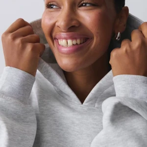 Ljusgrå gina hoodie - Säljer en ljusgrå hoodie med huva. Tröjan har ribbade muddar vid ärmslut och nederkant, samt en klassisk avslappnad passform. Perfekt för chill dagar eller när du vill ha något bekvämt och stilrent. Nypris 360kr mitt pris 180kr!