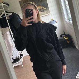 Stickad tröja med volanger - Svart stickad tröja med volanger, det är inte vita fläckar på bild nr 2 utan mönstret i stickningen som är som små hål! Från Vero Moda i storlek M, tar gärna emot prisförslag💕