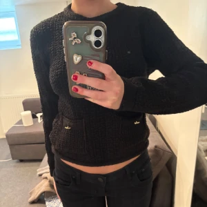 Svart stickad tröja med fickor - Säljer en svart stickad tröja med långa ärmar och två små fickor framtill. Tröjan har en klassisk rund halsringning och en bekväm passform. Perfekt för kyligare dagar!