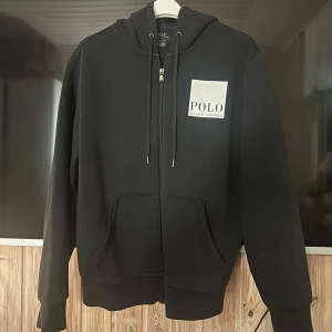 Ralph Lauren zip hoodie svart - Snygg svart hoodie från Polo Ralph Lauren med dragkedja och logga både fram och bak. Perfekt för en avslappnad stil. I mycket bra skick!